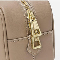 Taupe leather handbag with gold zipper pulls and detailed stitching closeup