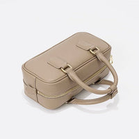 Taupe rectangular leather handbag with gold zipper and double handles on white background