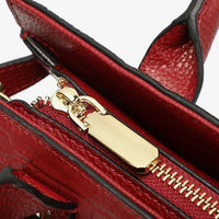 Close-up of red leather handbag with gold zipper and textured finish