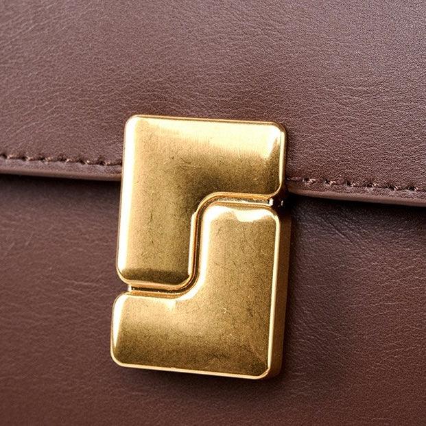 Brown leather bag with gold geometric clasp, close-up detail.
