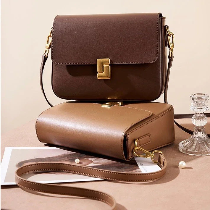 Two stylish leather crossbody bags in brown tones with gold hardware on a neutral background