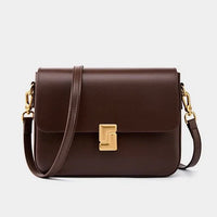 Brown leather crossbody bag with gold clasp and hardware on a plain background