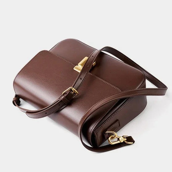 Brown leather crossbody bag with gold buckle on white background