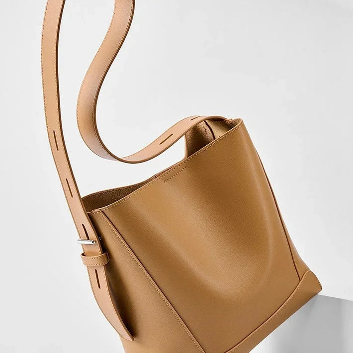Tan leather bucket bag with adjustable strap on a white background