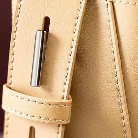 Close-up of beige leather bag strap with silver buckle and fine stitching detail