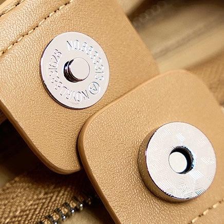 Close-up of tan leather bag with magnetic snap buttons and visible stitching
