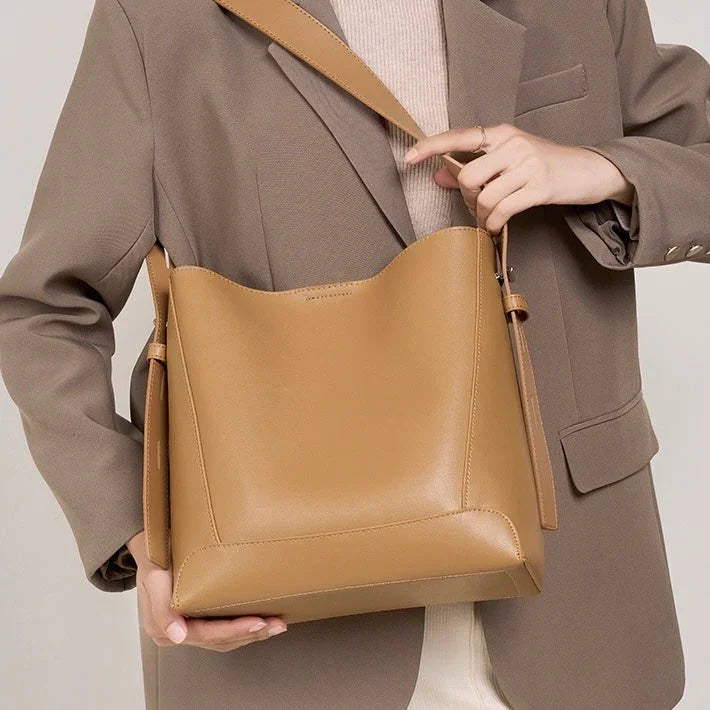 Woman in beige blazer holding large tan leather shoulder bag