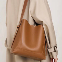 Woman wearing beige trench coat with large brown leather shoulder bag