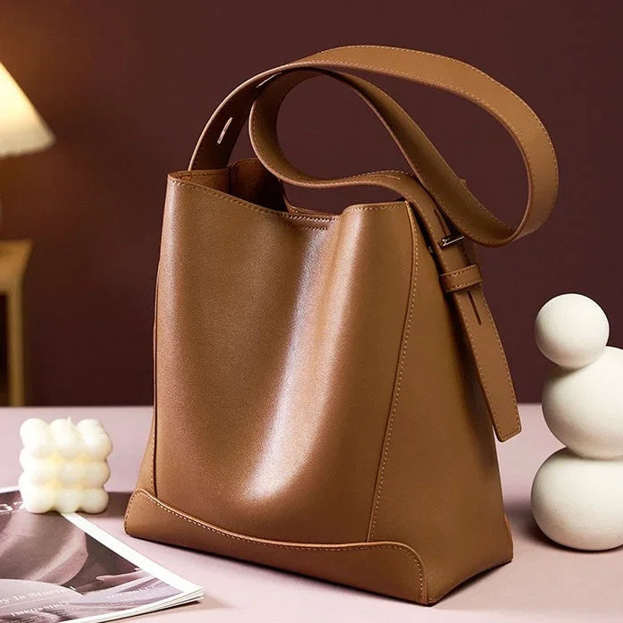 Brown leather tote bag on a table with candle, magazine, and modern decor