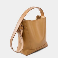 Tan leather tote bag with wide adjustable shoulder strap on a white background