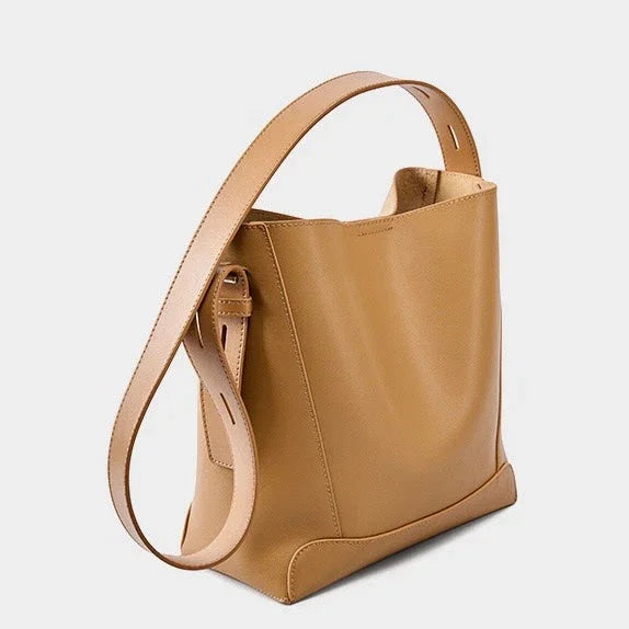 Tan leather tote bag with wide adjustable shoulder strap on a white background