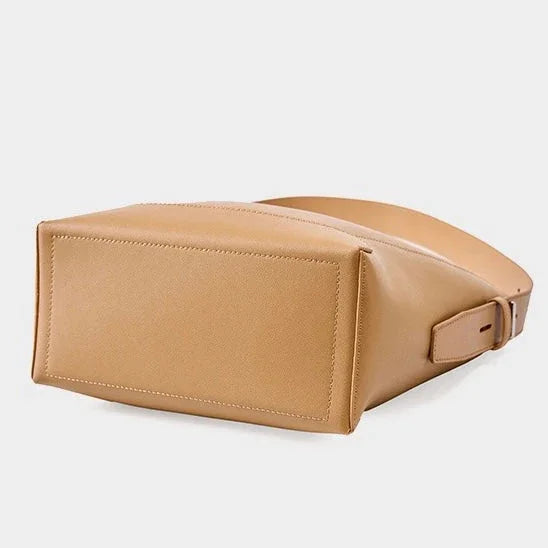 Tan leather crossbody bag with a rectangular base on a white background