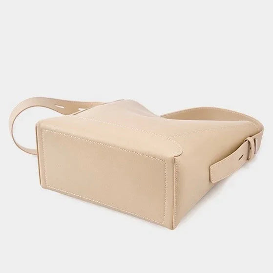Beige leather crossbody bag with adjustable strap on white background