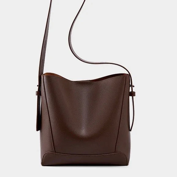 Brown leather bucket bag with adjustable shoulder strap on white background