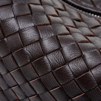 Close-up of dark brown woven leather handbag texture with visible zipper detail
