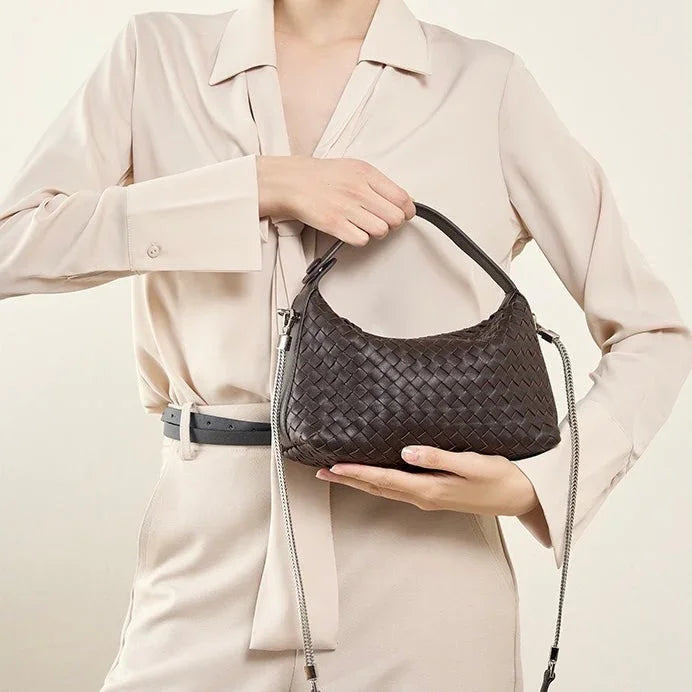 Woman in beige outfit holding a black woven leather handbag with shoulder strap