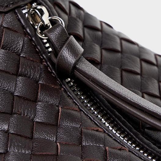 Close-up of woven dark brown leather bag with metal zipper and leather pull tab