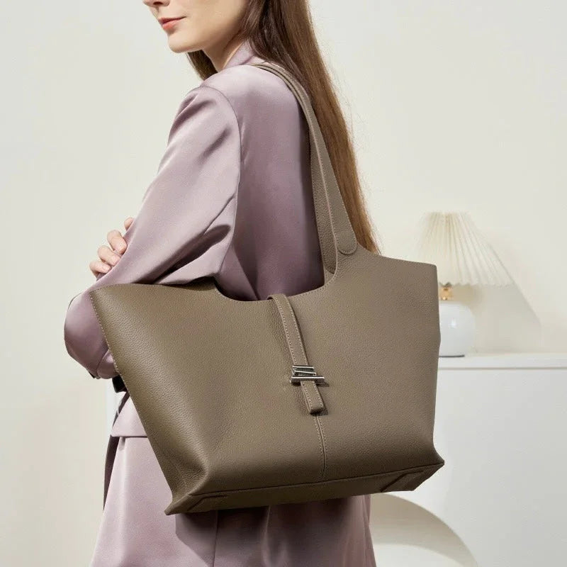 Woman in mauve blazer carrying a large taupe leather tote bag, minimal modern interior