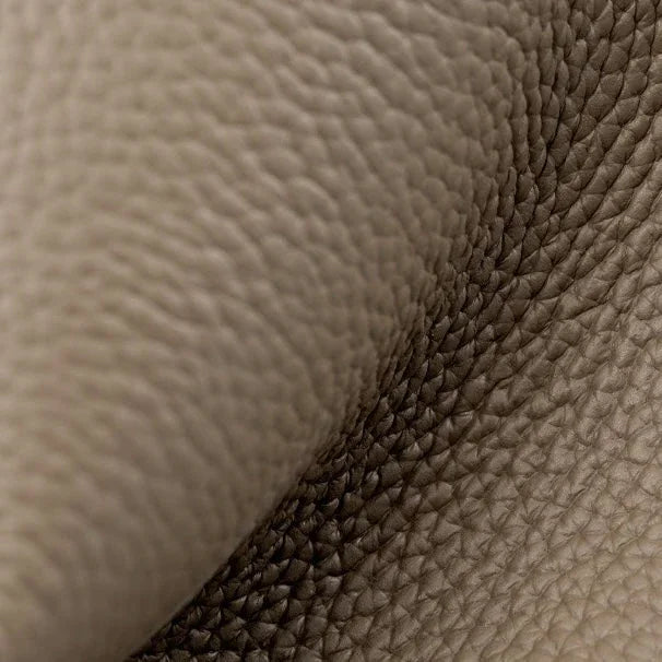 Close-up of beige pebbled leather texture with natural grain folds, luxury upholstery material