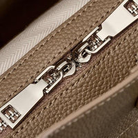 Close-up of beige leather bag with silver chain detail and textured surface
