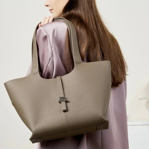 Taupe leather tote bag on woman's shoulder, minimalist fashion accessory