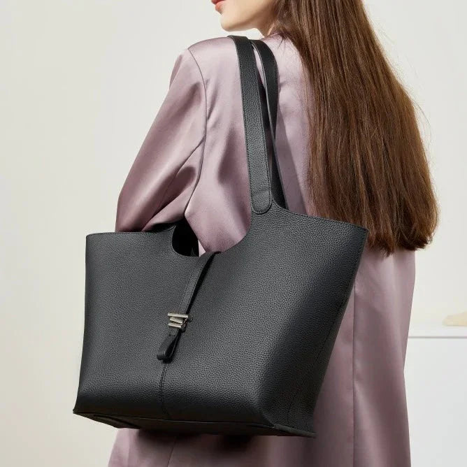 Woman wearing a black leather tote bag over shoulder, with lavender satin blouse
