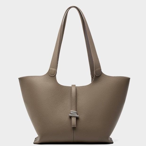 Taupe leather tote bag with dual handles and silver accent buckle on white background