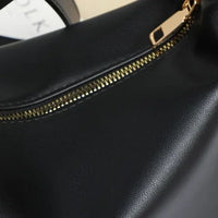 Close-up of black leather handbag with gold zipper detail
