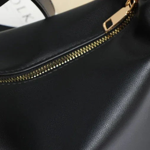 Close-up of black leather handbag with gold zipper detail