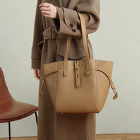 Woman in brown coat with tan leather tote bag, modern minimalist fashion style