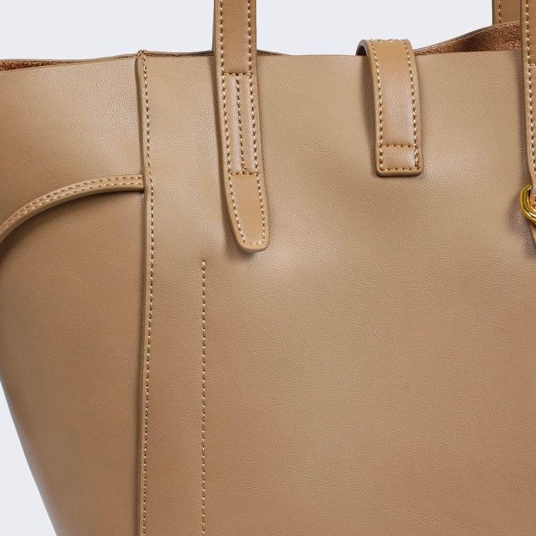 Close-up of tan leather tote bag with double handles and gold hardware