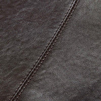 Close-up of dark brown leather upholstery with visible stitching seam
