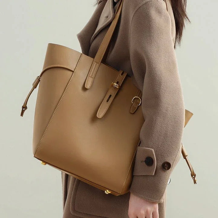 Woman wearing beige coat carrying large tan leather tote bag