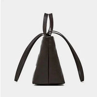 Side view of black leather bucket bag with top handles and drawstring straps