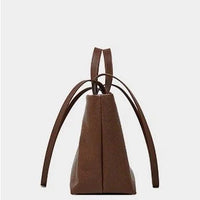Side view of brown leather tote bag with double handles on plain white background