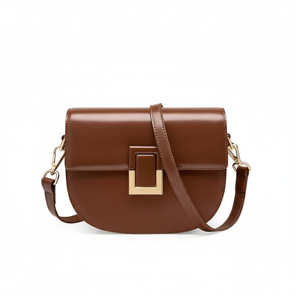 Brown leather crossbody bag with gold buckle and adjustable strap on white background