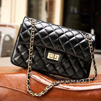 Black quilted leather handbag with gold chain strap and clasp on a brown leather surface