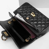 Black quilted leather handbag with gold clasp, open to show phone inside