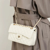 Quilted white leather handbag with gold chain strap on woman in taupe trench coat