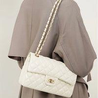 Quilted white leather shoulder bag with gold chain strap on person in taupe coat