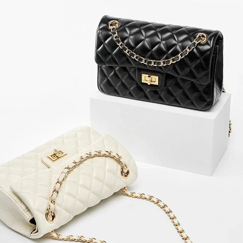 Quilted black and white leather handbags with gold chain straps on white display blocks