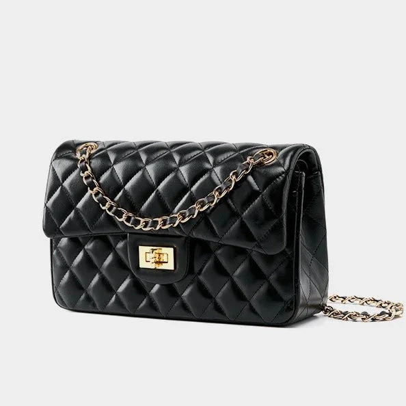 Black quilted leather handbag with gold chain strap and gold turn-lock clasp on white background