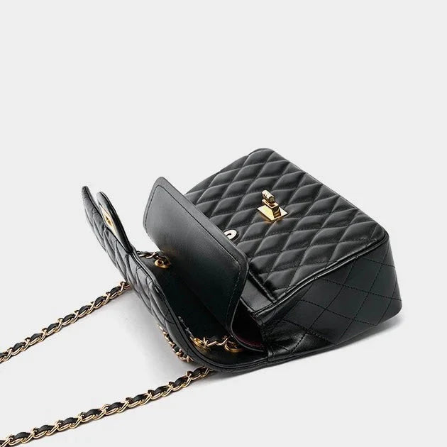 Black quilted leather shoulder bag with gold chain strap and clasp, open on white background