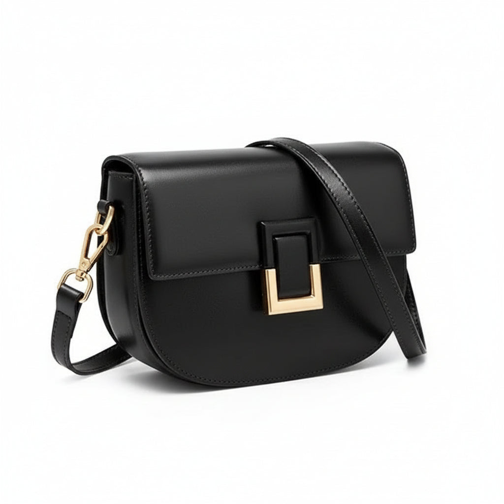 Black leather crossbody bag with gold buckle and adjustable strap on white background