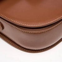 Close-up of brown leather handbag with detailed stitching on white background