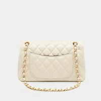 Cream quilted leather shoulder bag with gold chain strap on white background
