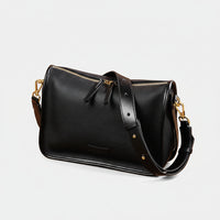 Black leather handbag with gold hardware on woven mat, rustic decor, dried flowers