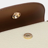 Close-up of a brown and cream leather handbag with gold magnetic snap closure