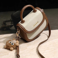 Beige and brown textured leather crossbody handbag with handle and plush bear keychain