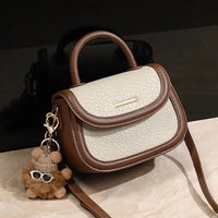Small beige and brown leather crossbody handbag with top handle and cute bear keychain